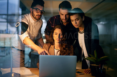 Buy stock photo Shot of a group of businesspeople using a laptop while working overtime in the office