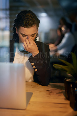Buy stock photo Shot of a tired businesswoman holding her head while working late in the office
