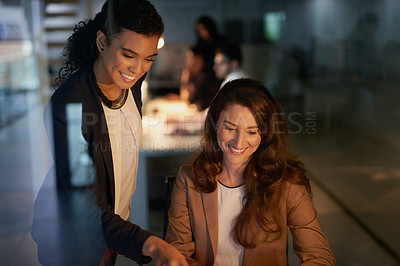 Buy stock photo Shot of two businesswomen working overtime together in the office