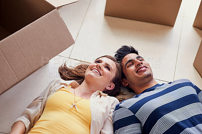 Buy stock photo Shot of a young couple lying on the floor while taking a break from moving into a new home