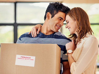 Buy stock photo Shot of a affectionate young couple carrying boxes on moving day
