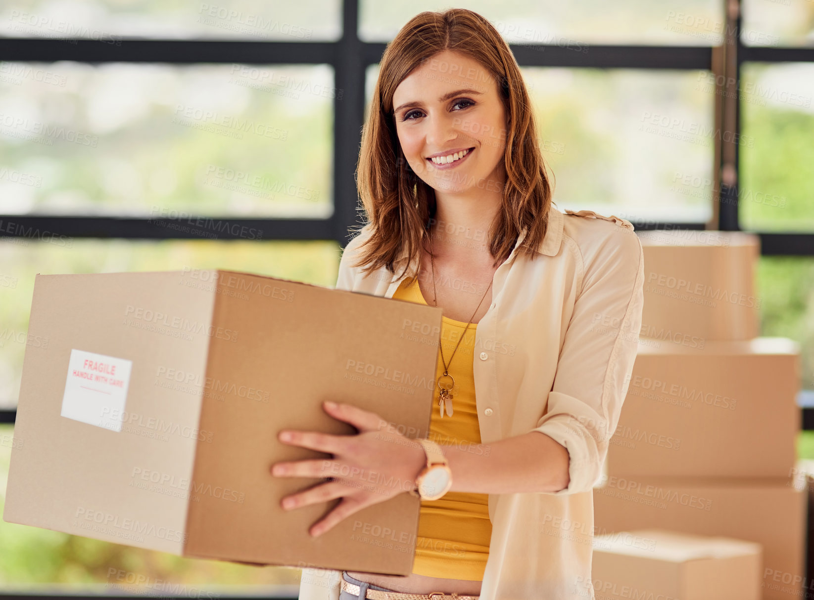Buy stock photo Portrait of a smiling young woman carrying a box on moving day