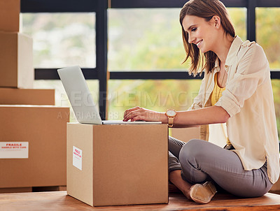Buy stock photo Shot of a young woman using a laptop while taking a break from moving into a new home