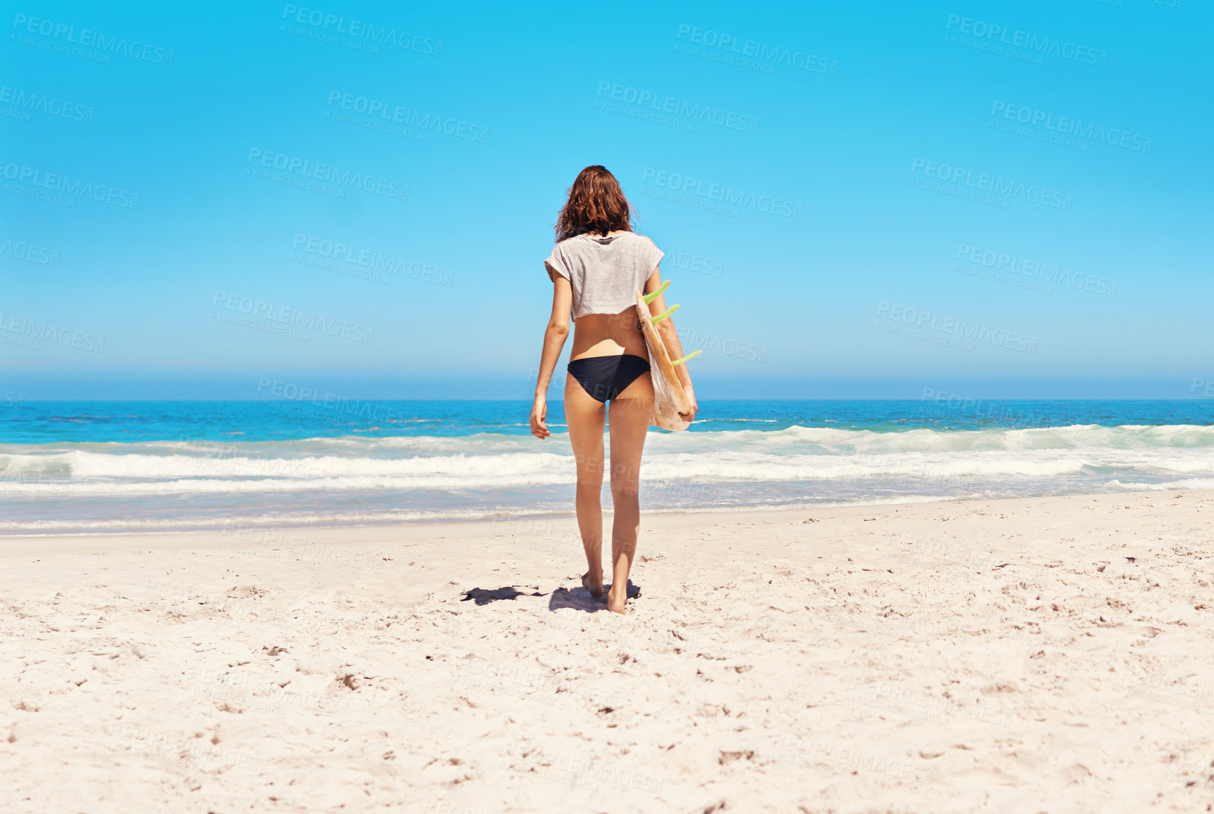 Buy stock photo Rearview shot of a sexy young woman walking towards the ocean with her surfboard