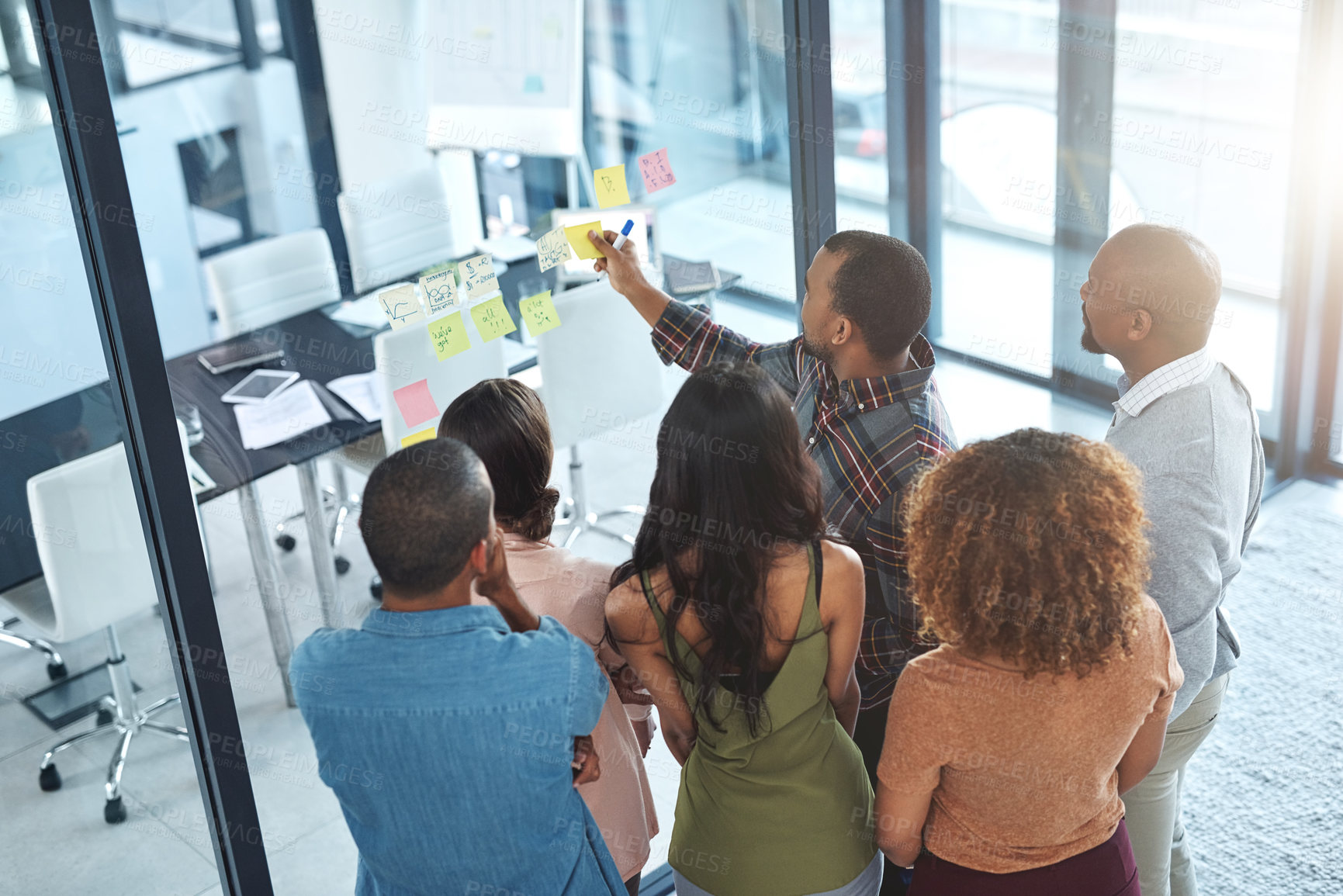 Buy stock photo High angle shot of a group of coworkers brainstorming on a glass wall