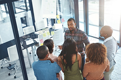 Buy stock photo High angle shot of a group of coworkers brainstorming on a glass wall