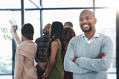 Buy stock photo Shot of a handsome mature man standing in the office with his colleagues in the background