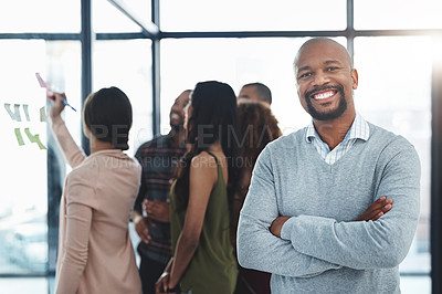 Buy stock photo Portrait of a handsome mature man standing in the office with his colleagues in the background