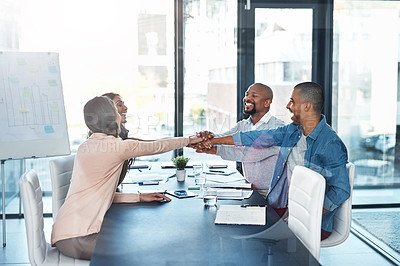 Buy stock photo Shot of a group of coworkers sitting around the boardroom table with their hands in a huddle