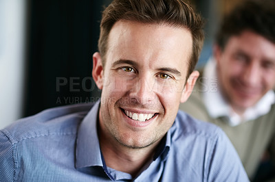 Buy stock photo Portrait of a smiling young professional sitting in an office with colleagues in the background