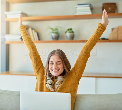 Buy stock photo Shot of an attractive young woman raising her arms in triumph while using her laptop at home
