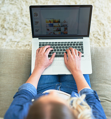 Buy stock photo High angle shot of an unrecognizable young woman using her laptop while sitting on the sofa at home