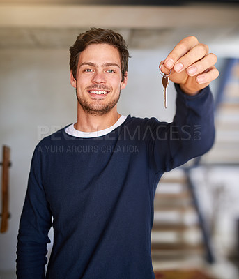 Buy stock photo Portrait of a happy young man holding up the key to his new home