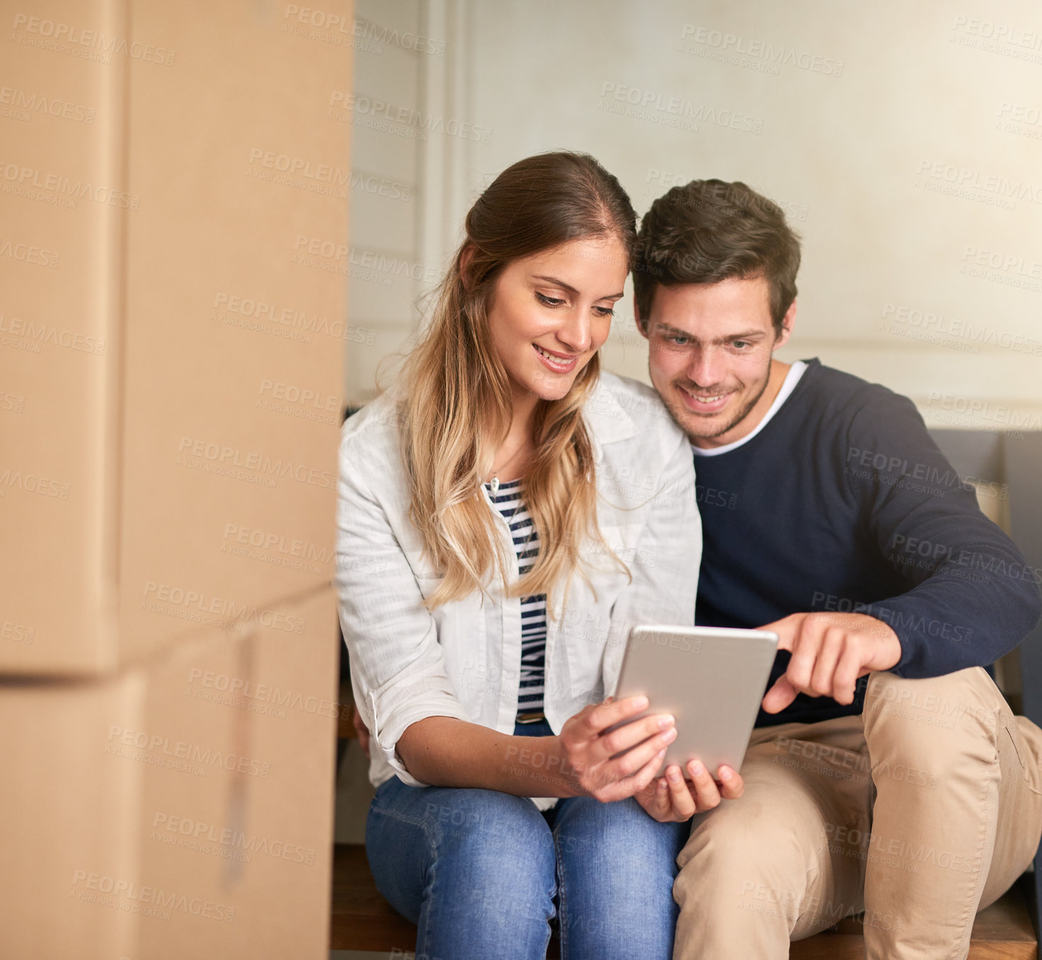 Buy stock photo Happy couple, new home and browsing with tablet by boxes for moving in, renovation or relocation. Young man and woman with smile on technology for house decor, ideas or furniture for interior design