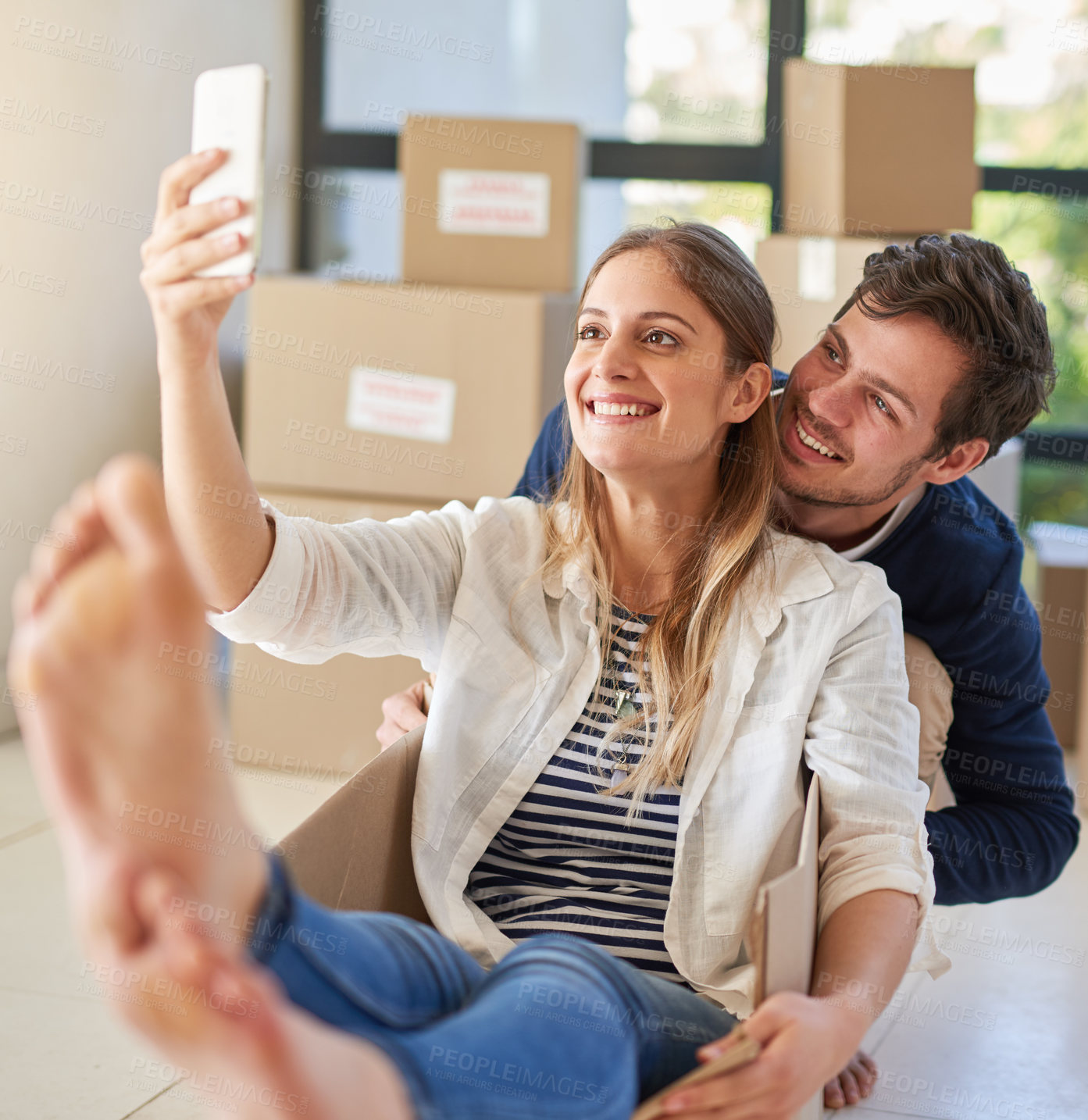 Buy stock photo Happy couple, relax and moving in with selfie in box for photography, new home or picture at apartment. Man and woman with smile, boxes or playing for memory in house, investment or property together
