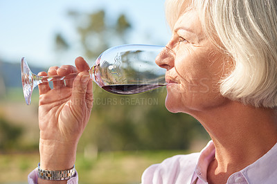 Buy stock photo Closeup shot of a senior woman drinking a glass of red wine outside