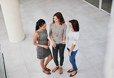 Buy stock photo Shot of three businesswomen looking at a tablet together while standing in the office