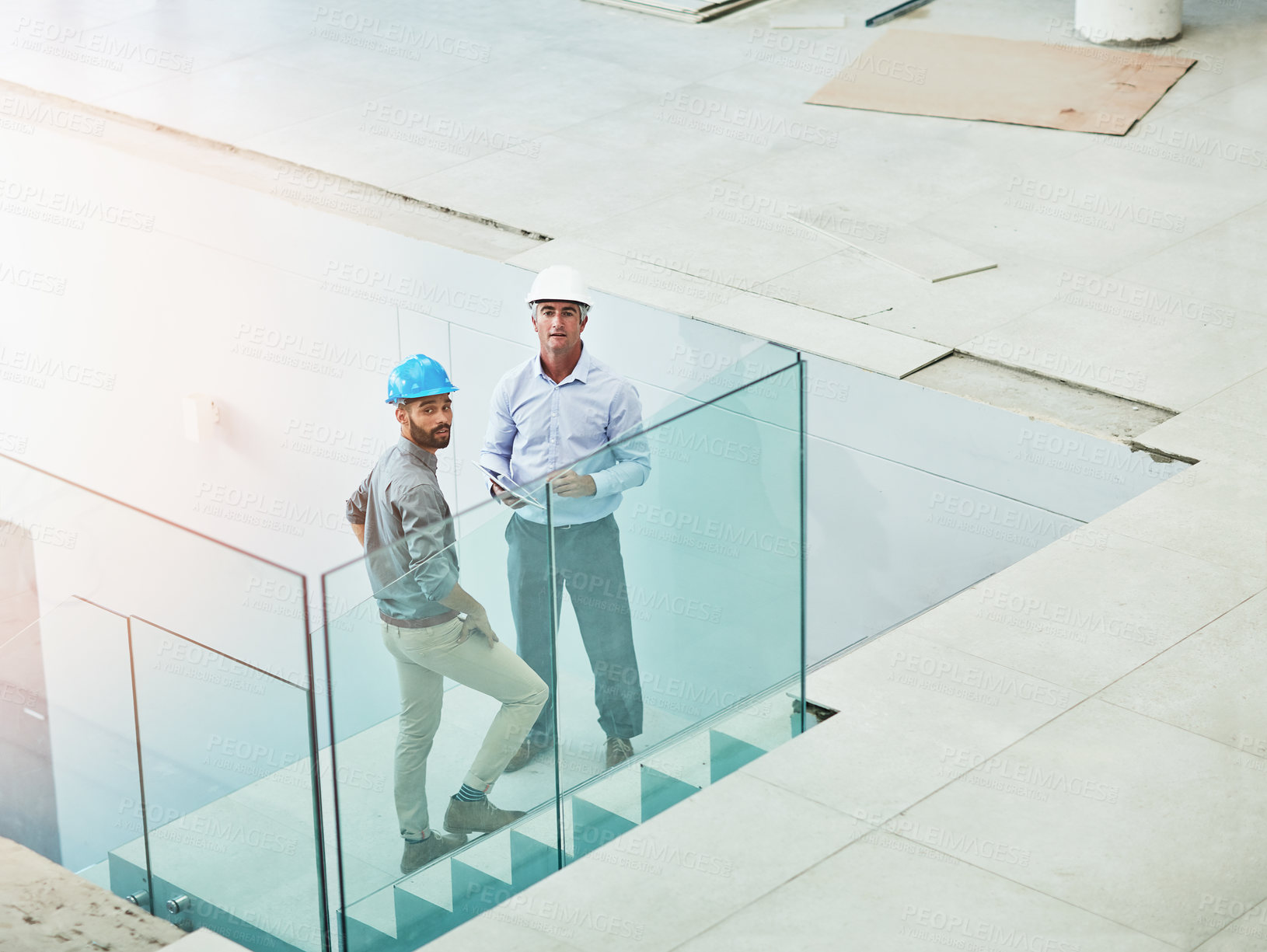 Buy stock photo Shot of two architects doing an inspection of their site while wearing hardhats