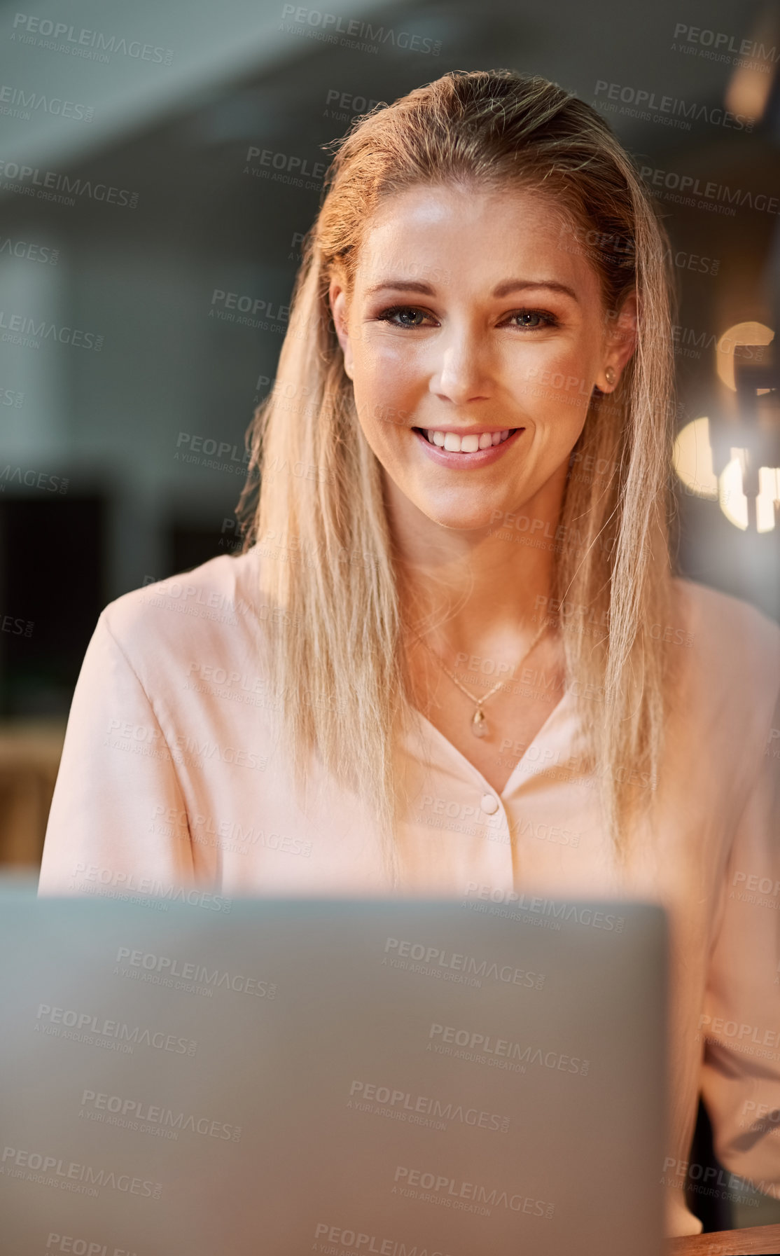 Buy stock photo Portrait of a smiling young businesswoman working on a laptop in an office