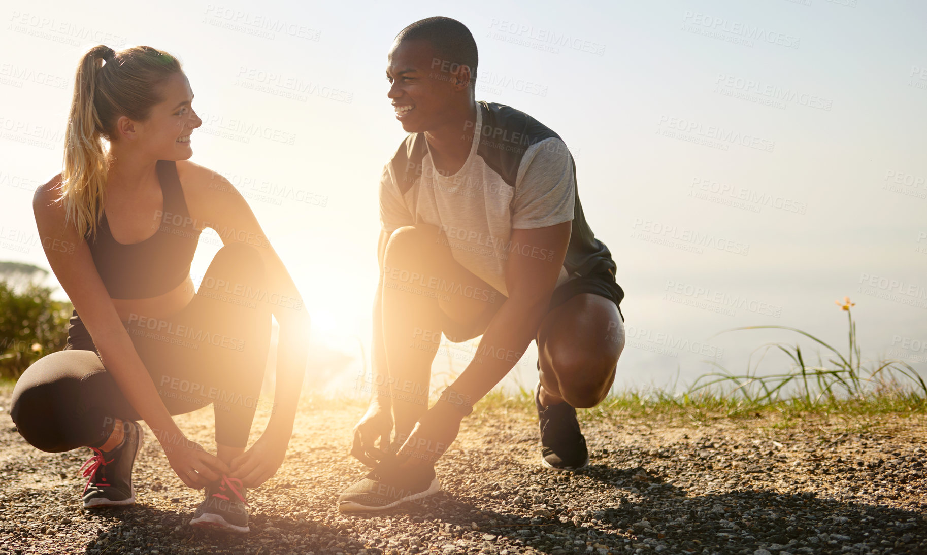 Buy stock photo Shot of a fit young couple tying their shoelaces before a run outdoors