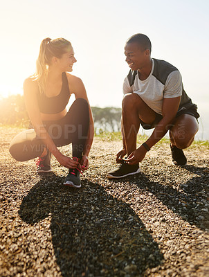 Buy stock photo Shot of a fit young couple tying their shoelaces before a run outdoors