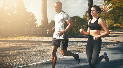 Buy stock photo Shot of a fit young couple going for a run outdoors