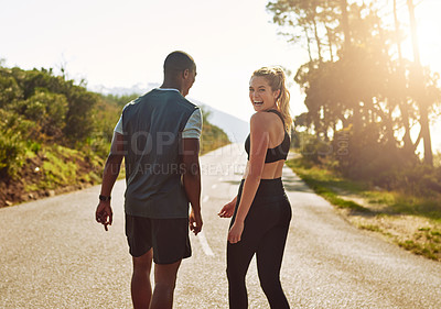 Buy stock photo Shot of a fit young couple slowing down for a walk during their run outdoors