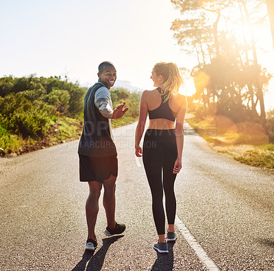 Buy stock photo Shot of a fit young couple slowing down for a walk during their run outdoors