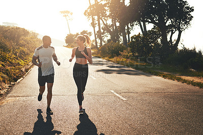 Buy stock photo Shot of a fit young couple going for a run outdoors