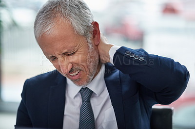 Buy stock photo Shot of a mature businessman suffering from neck pain while working in an office