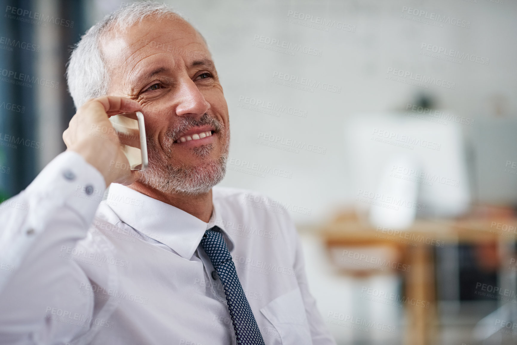 Buy stock photo Shot of a smiling mature businessman talking on a cellphone while working in an office