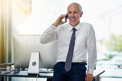 Buy stock photo Shot of a smiling mature businessman talking on a cellphone while working in an office