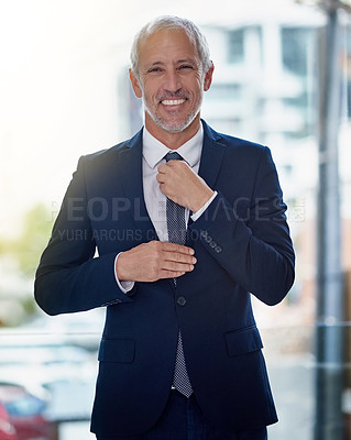 Buy stock photo Portrait of a smiling mature businessman adjusting his tie while standing in an office