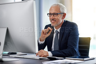 Buy stock photo Shot of a smiling mature businessman working at his desk in an office