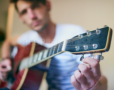 Buy stock photo Shot of a handsome young man playing guitar at home