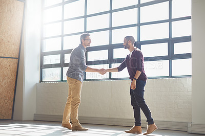 Buy stock photo Shot of two businessmen shaking hands in the office