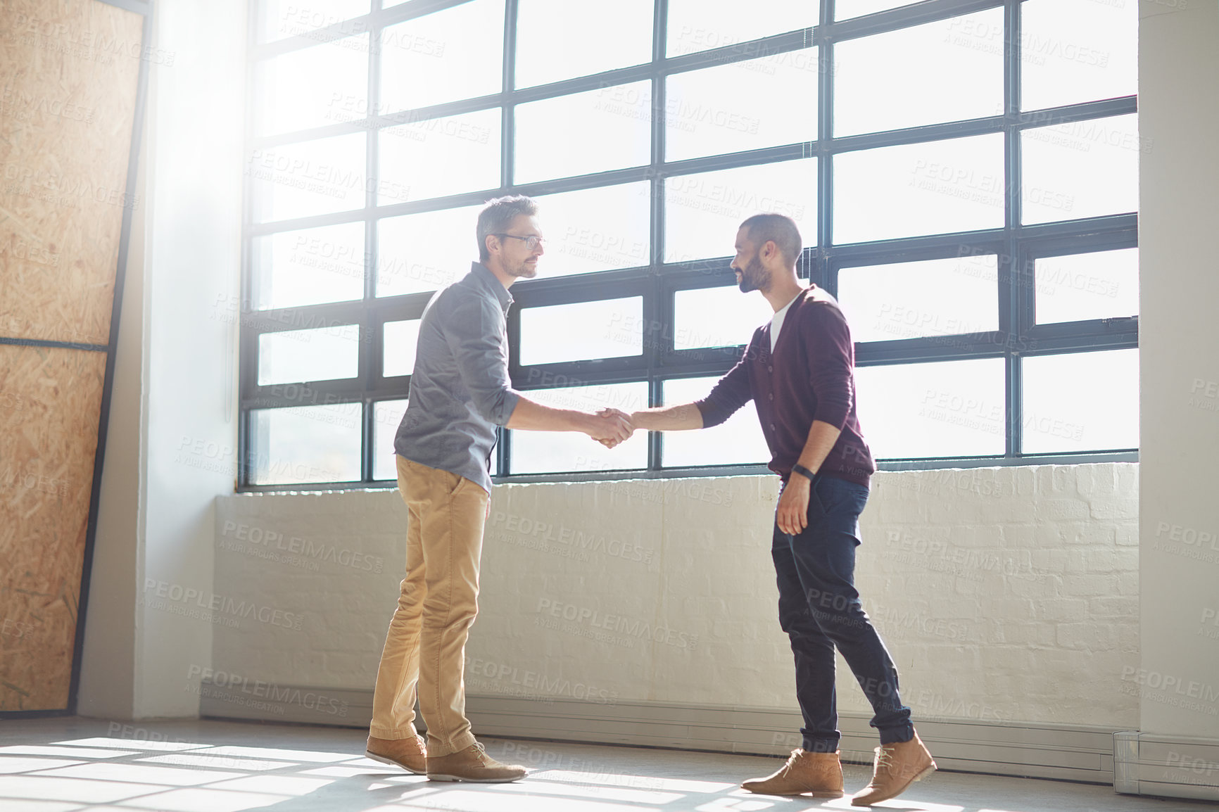 Buy stock photo Shot of two businessmen shaking hands in the office