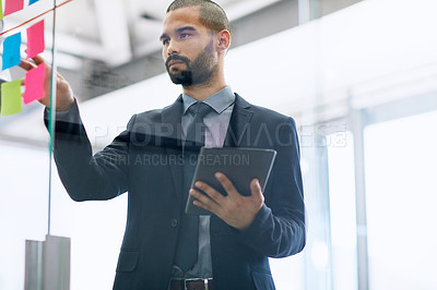 Buy stock photo Shot of a serious young businessman working alone in the office