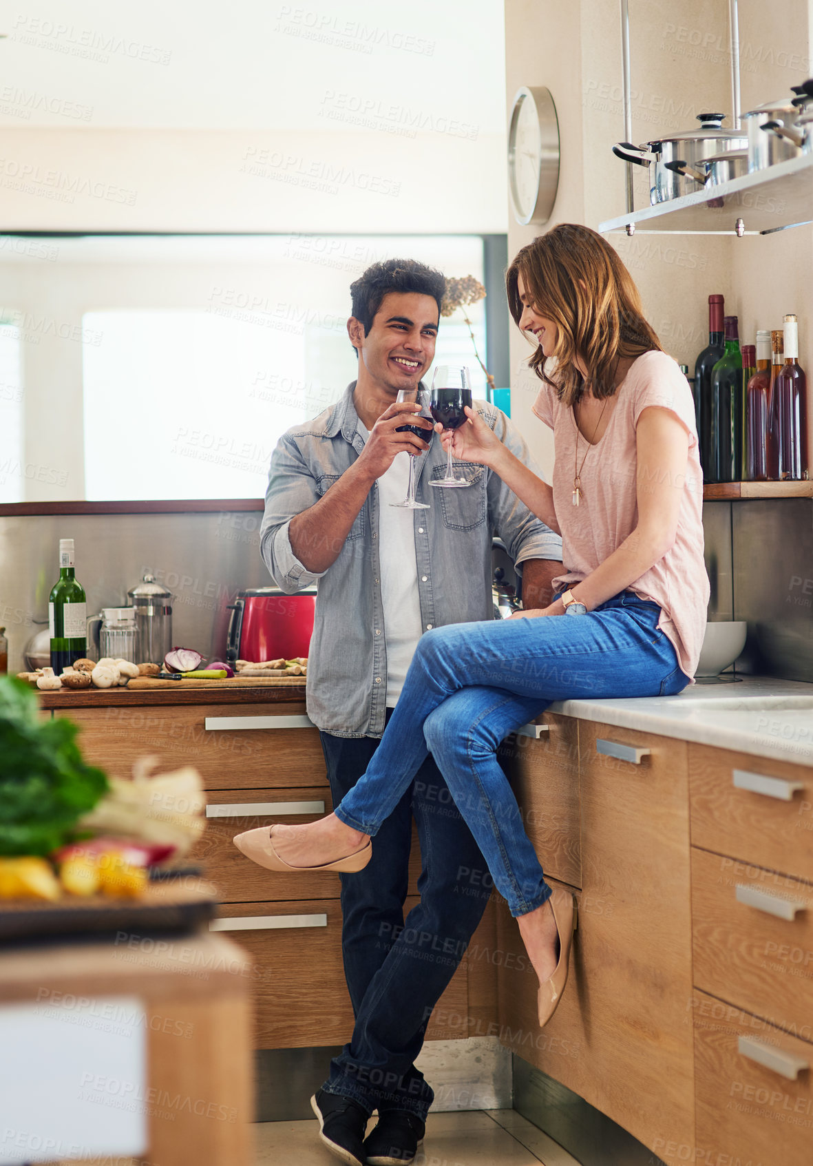 Buy stock photo Happy, couple cooking and drinking together for bonding in kitchen over romantic meal preparation at home. Excited, man and woman with wine glasses and cutting board for nutrition and healthy food