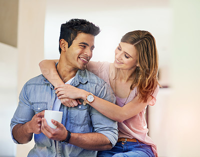 Buy stock photo Shot of an affectionate young woman sitting with her arms around her husband at home