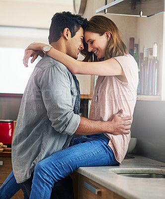 Buy stock photo Shot of an affectionate young couple arm in arm in the kitchen