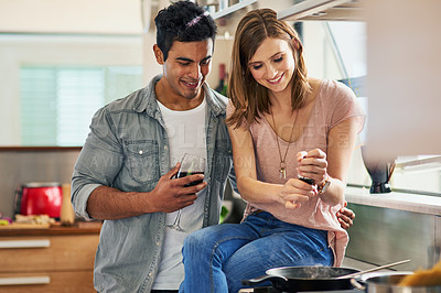 Buy stock photo Shot of an attractive young couple drinking wine and cooking