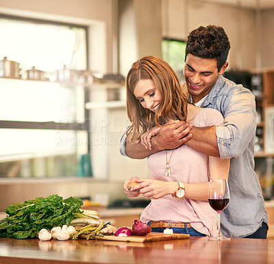 Buy stock photo Shot of a young man hugging his wife while she prepares dinner