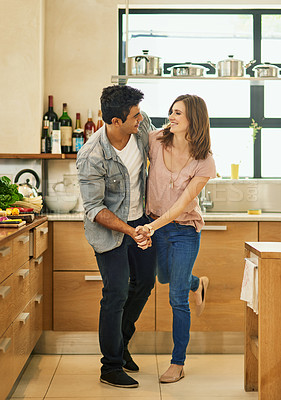 Buy stock photo Shot of an affectionate young couple dancing in the kitchen