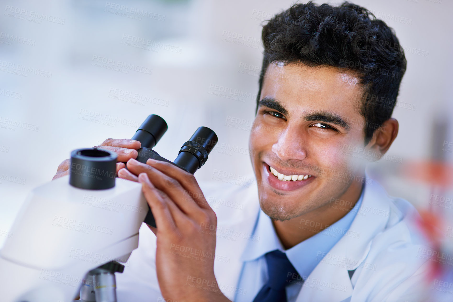 Buy stock photo Portrait of a smiling lab technician using a microscope while sitting in a lab