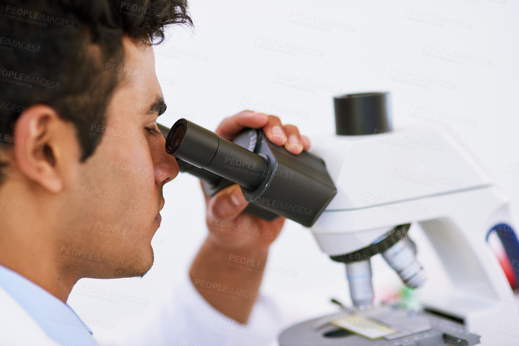 Buy stock photo Shot of a lab technician using a microscope while sitting in a lab