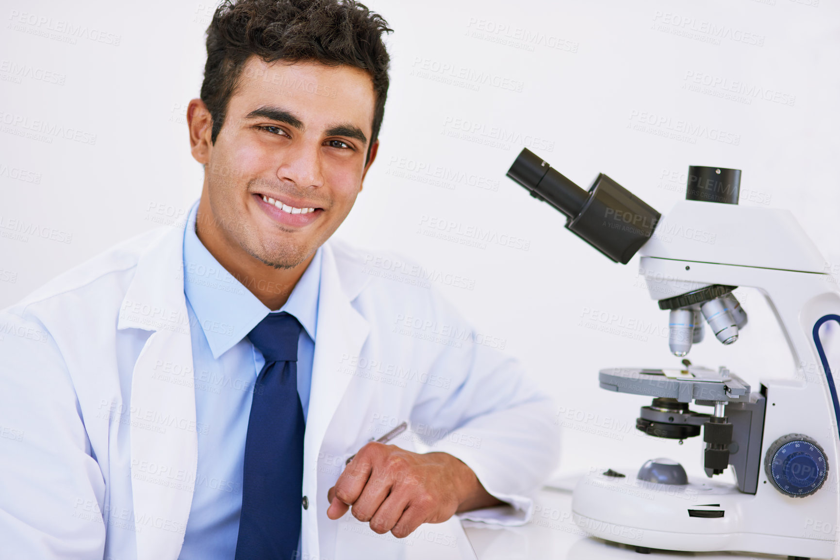 Buy stock photo Portrait of a smiling lab technician using a microscope while sitting in a lab