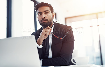 Buy stock photo Shot of a handsome businessman sitting behind his laptop