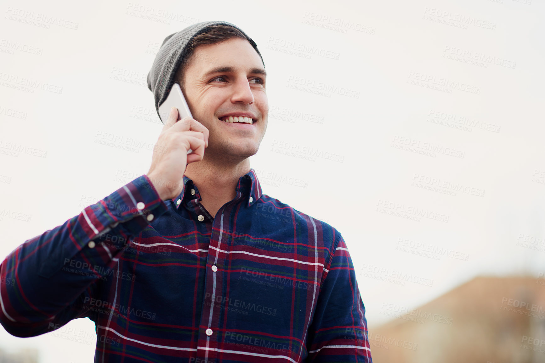 Buy stock photo Shot of a handsome young man talking on his cellphone while walking through the city