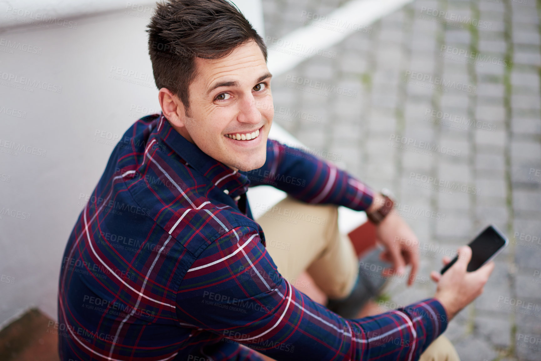 Buy stock photo High angle portrait of a handsome young man sitting on some steps outside